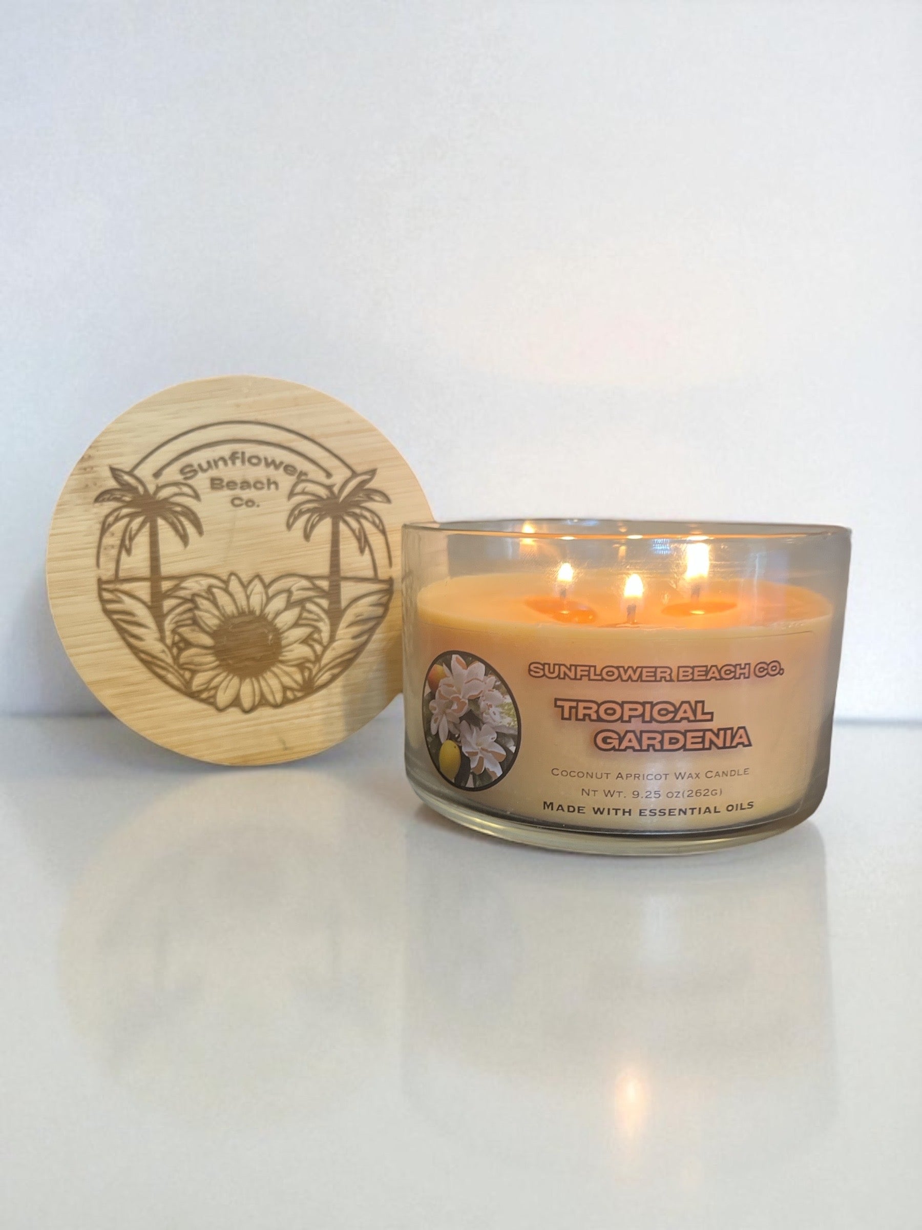 Showcasing the bamboo engraved lid with the sunflower beach logo and tropical gardenia three wick candle